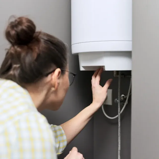 Homeowner listening to a noisy water heater in a Mesa, AZ home Homeowner listening to a noisy water heater in a Mesa, AZ home