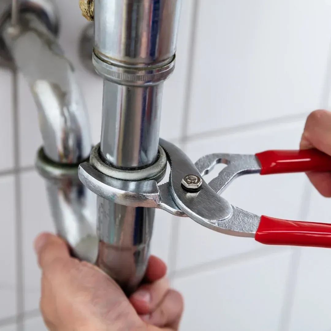 Plumber tightening a slip joint nut on a chrome drain pipe during water leak repair in Mesa, AZ Plumber tightening a slip joint nut on a chrome drain pipe during water leak repair in Mesa, AZ